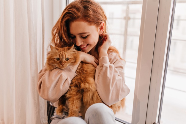 Relaxed smiling girl playing with her fluffy cat